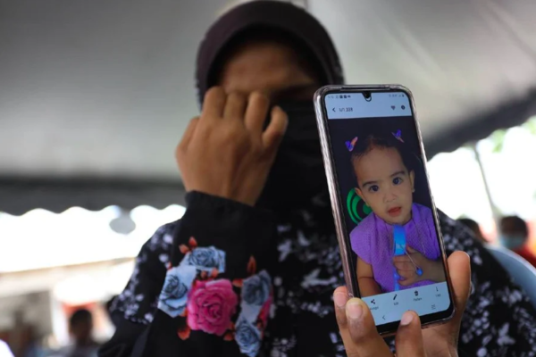 The grieving mother holding her phone to show a photo of Zahida.