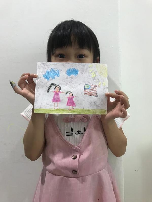 Esther's daughter with her drawing depicting her and her mother with the Jalur Gemilang.