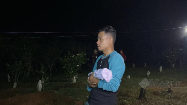 Mohd Khairul Asyraf Nor Azman holding his unborn son who was laid to rest at the Kampung Charuk Bemban Dalam Cemetery on 6 July.