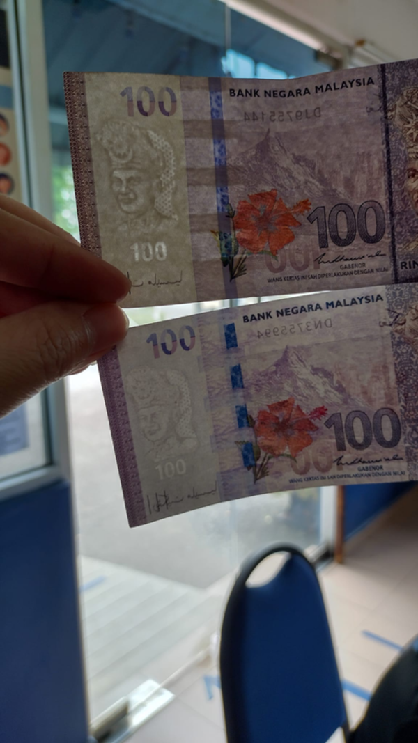 The banknote on top is real, while the one below is fake.