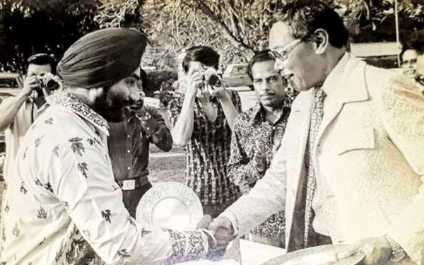 Sukhdev receiving the pewter plaque, presented by Shafie.