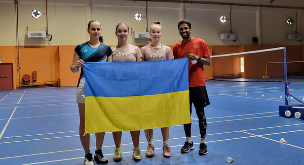 The players, Zharka, Mariia, and Polina with their coach Salim, holding the Ukrainian flag.
