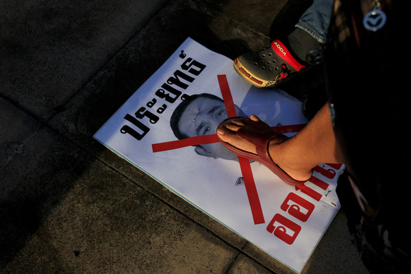 Protestor steps on a poster showing Prayut.