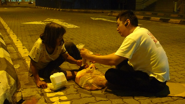 Justin handing over food to a mentally-disabled woman, who was living by the roadside.