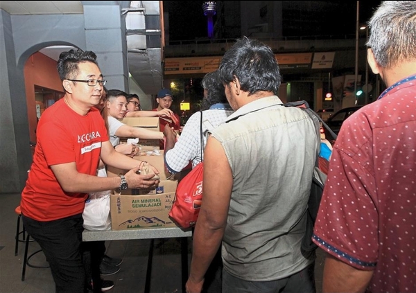 Justin giving food to the homeless in Anjung Singgah.