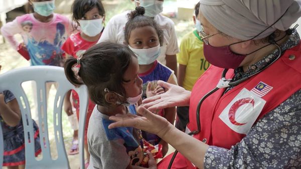 Professor Tan Sri Dr Jemilah treating patients during a disaster relief programme at a clinic for flood-affected Orang Asli.