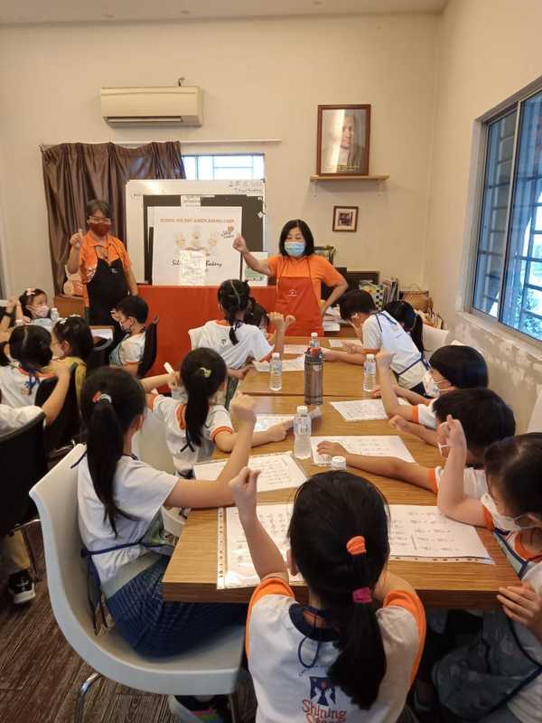 Leong teaching sign language to 21 children from Charis Shining Stars during the School Holiday Baking Camp at Silent Teddies Bakery.