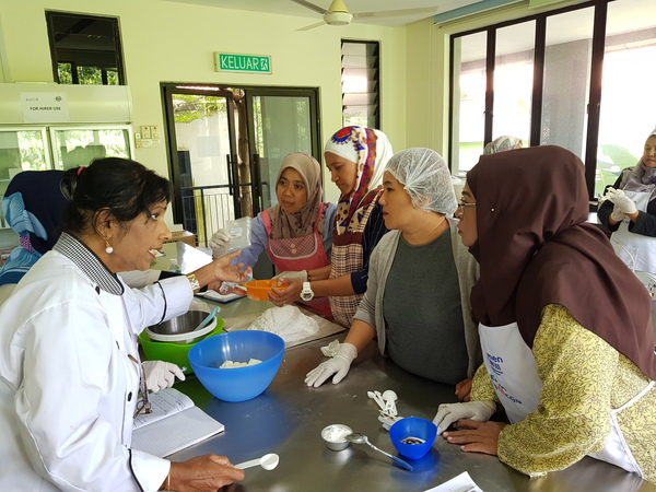 A WOW community leader conducting a baking class for a group of women.