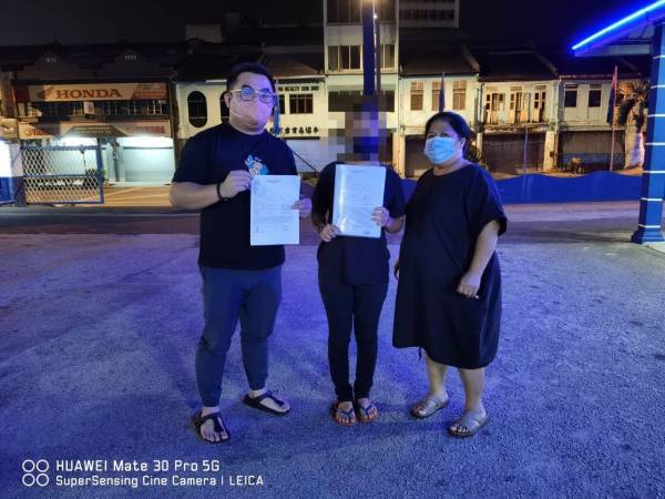 Zhan (middle) pictured with two volunteers from the children's shelter, outside the Johor Jaya police station after filing a police report against Zhan's mother.