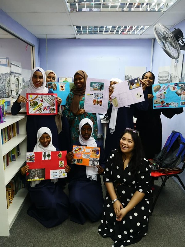 Jasmine with Fugee students of the Girls Circle. The girls are holding up their vision boards, one of the activities they did as part of the programme.