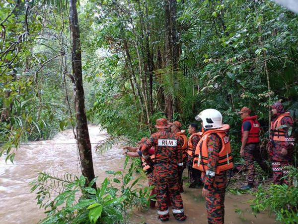 Firefighters crossing the river using a rope-bound rescue technique to reach the trapped victims.