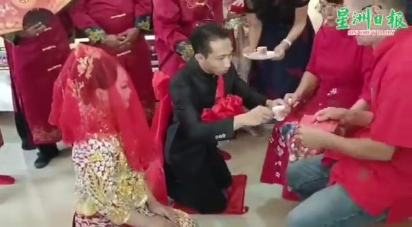 The bride and groom kneeling in front of the bride's parents to present them with tea during the tea ceremony.