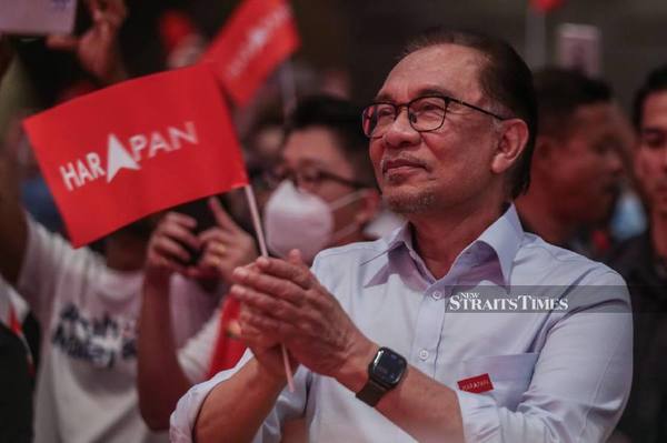 Photo of Anwar Ibrahim holding the Pakatan Harapan flag at an event.