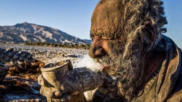 Haji smokes from a pipe showing his uncanny lifestyle.