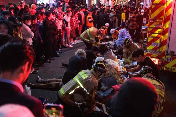 Photo of emergency workers tending to injured as a group of onlookers watch.