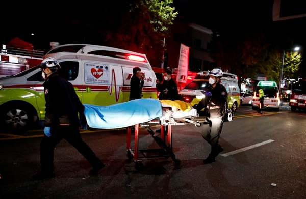 Photo of two emergency responders moving a victim on a stretcher after the stampede.