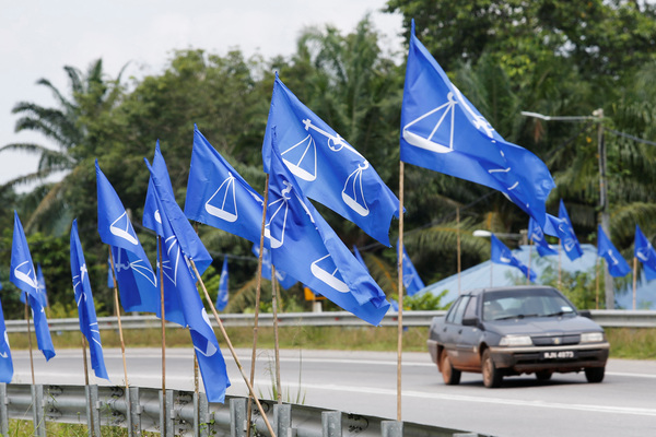 A car is seen behind flags of BN ahead of the upcoming 15th General Election in Bera, Pahang.