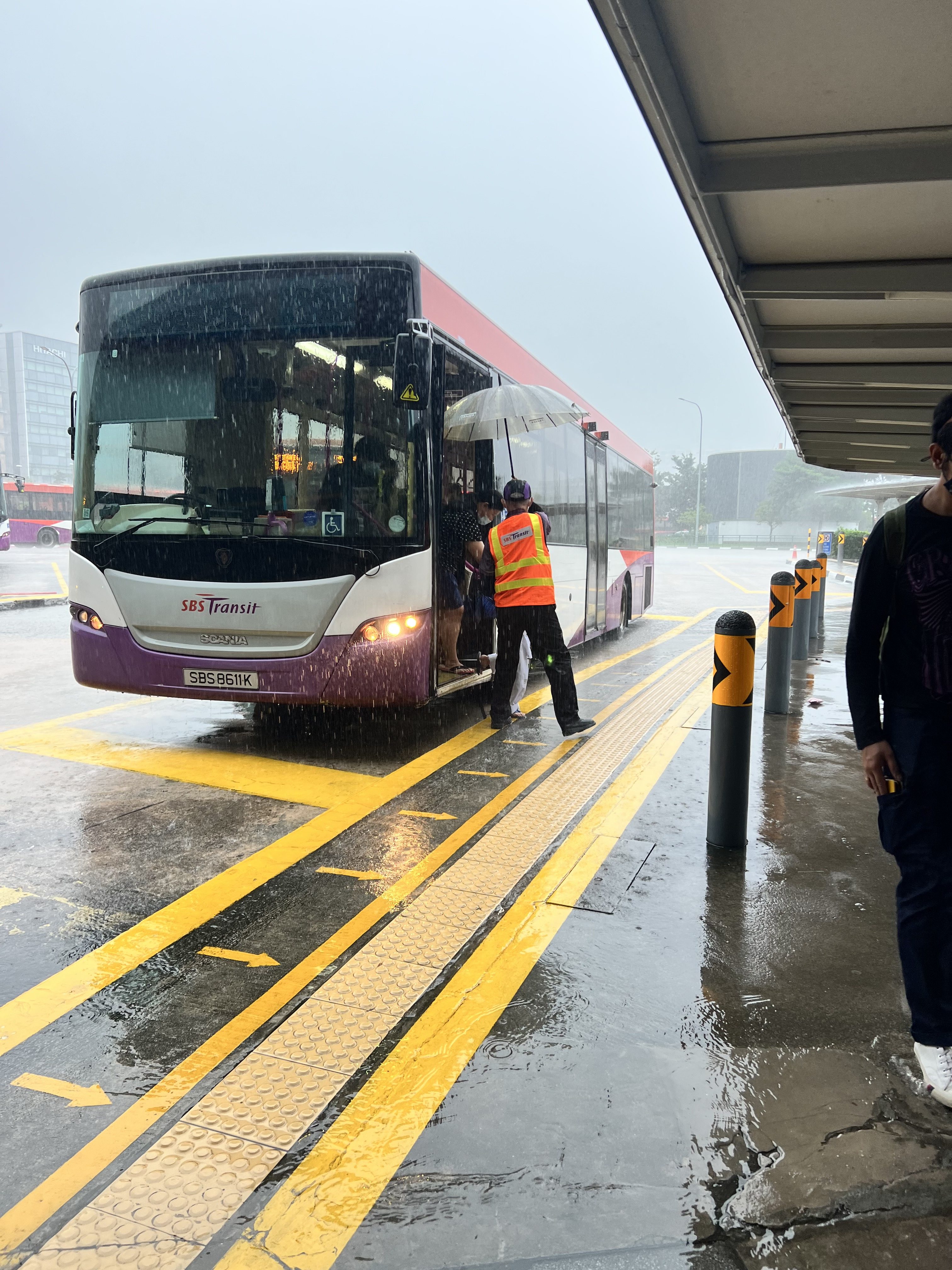 Le capitaine du bus abrite les passagers qui descendent sous la pluie battante pour se rendre à la gare