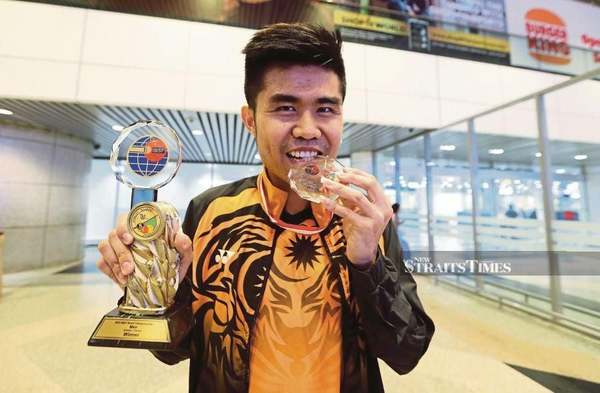 Lim posing with his trophy and medal at the Kuala Lumpur International Airport.