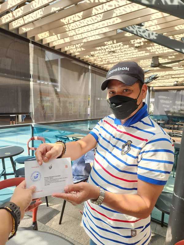 Melizarani handing her postal vote to collection volunteer, Abdul Rahman, in Singapore.