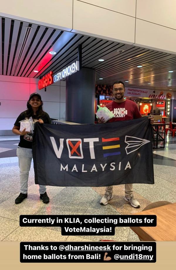 Undi18 co-founder Tharma Pillai (right) collecting postal votes from a returning Malaysian from Bali, Indonesia.