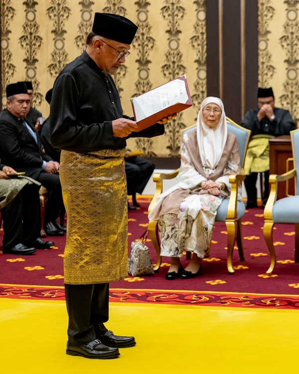 Anwar takes his oath of office while his wife, Dr Wan Azizah Wan Ismail, watches.