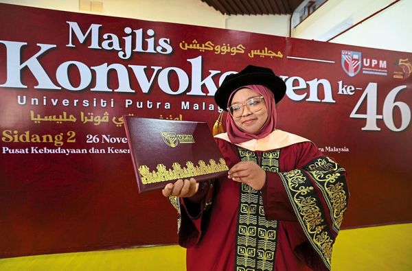 Norhidayu posing with her doctorate certificate.