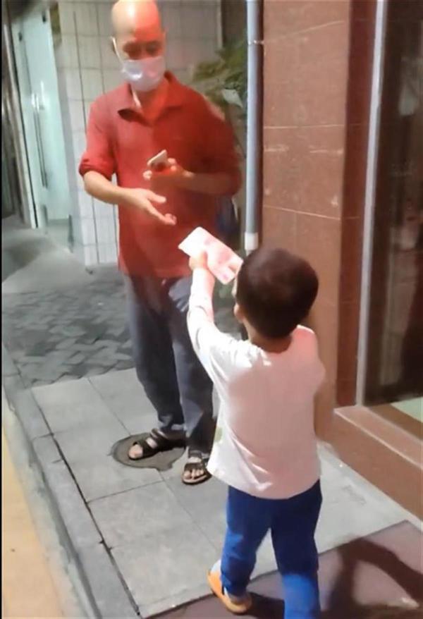 The young boy handing the money to the neighbour to pay for the damage he caused.