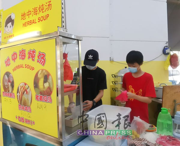 Amar Zaid Amir Lim (left) and his younger brother working at a herbal soup hawker stall.