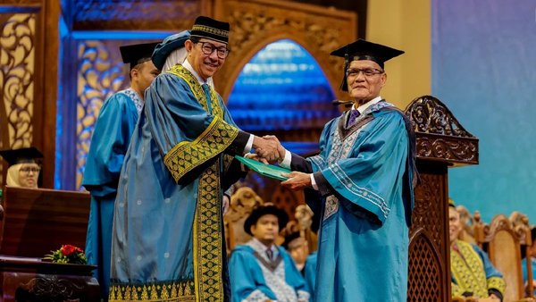 Tan Sri Adnan Yaakob (right) receiving his bachelor's degree certificate in law from UIAM professor Tan Sri Dr Dzulkifli Abdul Razak (left).