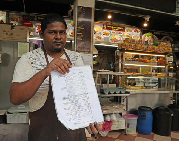 The employee showing the price chart of their food stall.