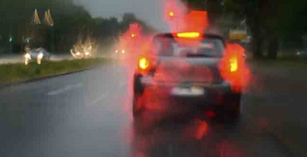 File photo of a car driving in rain with its third brake light visible.