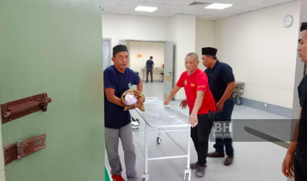 Photo of Ruslan (left) carrying his grandson's remains to be taken back to Labis, Segamat, for burial.