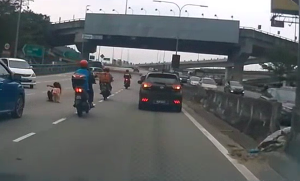 Screengrab from the video clip, showing the front passenger, who was thrown out of the Myvi and onto the middle lane, as vehicles pass by her.