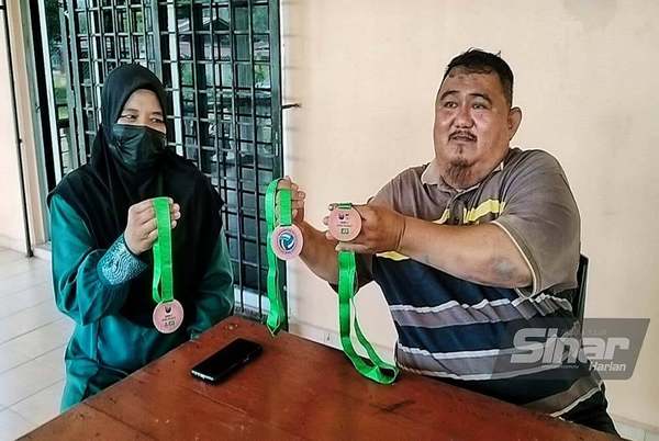 Photo shows Abd Halim (right) and his wife, Hartini Wagimun, showing the medals their daughters have won in volleyball.