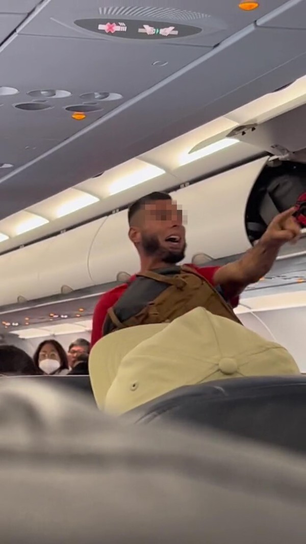 One of the rude men threatening a passenger on the plane.