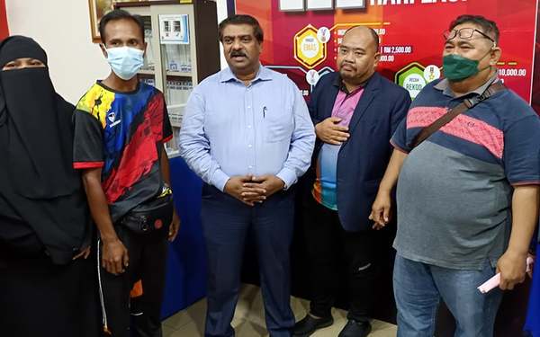 Photo of Saiful Hadee Amar (second from right) with the parents of the two players he slapped, while Shanmugam stands in the middle.