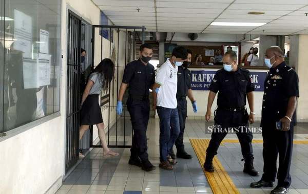 The photo shows the couple, with the husband in front and the wive behind him, being escorted by police officers at the Ampang Magistrate's Court on 4 January.