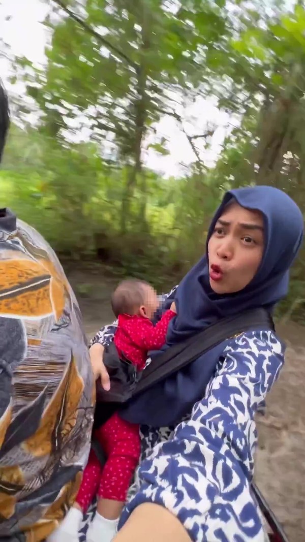 Ria carrying a sleeping Moana in her arms while she and her husband enjoy an ATV ride.