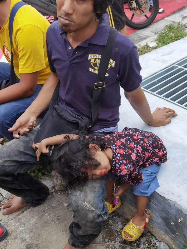 The father and daughter resting at the side of the road before being taken to the hospital.