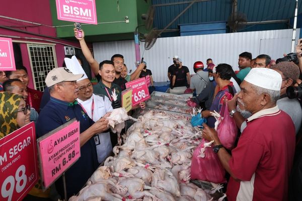 Mohamad Sabu (second left) holding a chicken while others look on at a chicken breeding, processing, and distribution company in Alor Setar, Kedah.