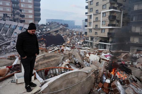 A man standing amid rubble looks at the damage following an earthquake in Hatay, Turkiye.