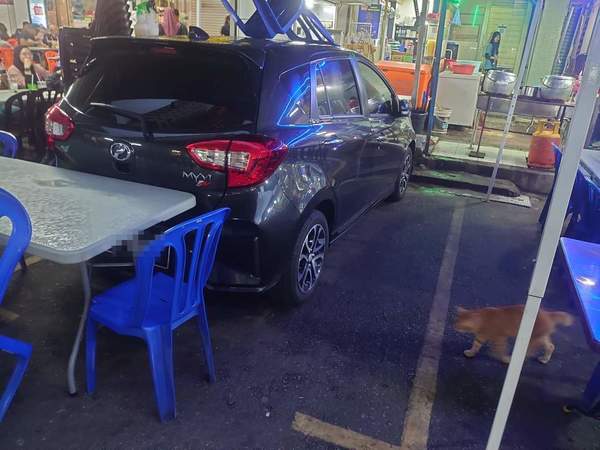 The Myvi barricaded into a parking space by tables and chairs.