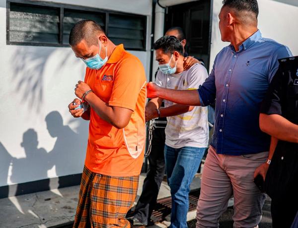 The accused, Nur Aslam Faizal (in white t-shirt) and Suffian Effendy Kadri, being escorted out of the court.