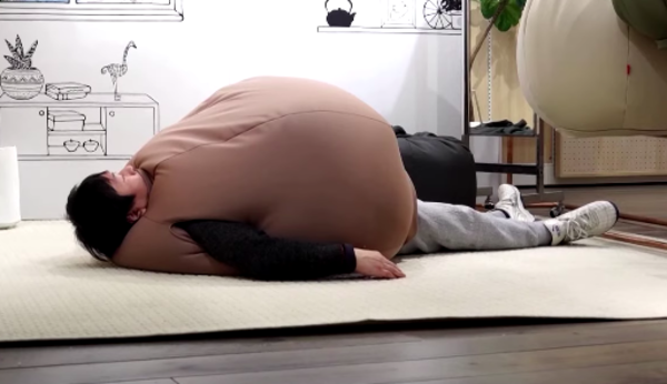 A man lying down in the wearable beanbag.