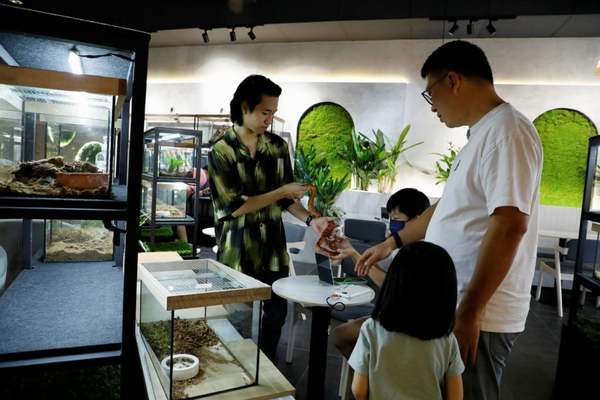 Yap (left) passing a corn snake to a curious customer.