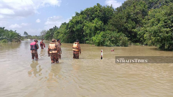 Firefighters searching for the woman after the car she was travelling in was swept away by floodwaters on Jalan Nitar Utama, Mersing.