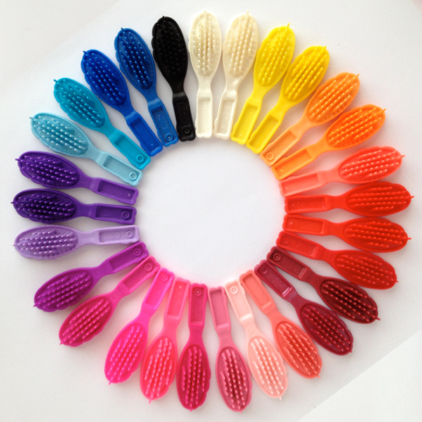 A collection of vintage Barbie doll hair brushes. These brushes were packaged with the doll and are bigger than the doll's hand.