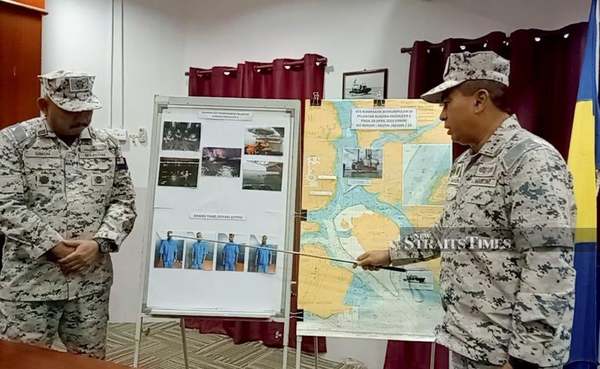 Malaysian Maritime Enforcement Agency (MMEA) acting director-general Vice-Admiral Datuk Saiful Lizan Ibrahim showing photos of the four suspects.