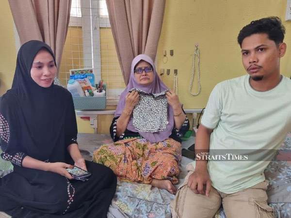 Imani's grandmother, Wan Maheran Omar (centre), showing the dress the child was wearing when she died.